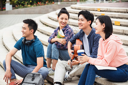 男人愉悦高兴的年轻的大学生坐在台阶上闲聊图片