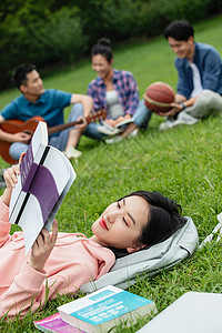 学生抱书青年女大学生在草地上享受课余时间背景