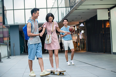 时尚帅气的大学生教女朋友滑滑板背景图片