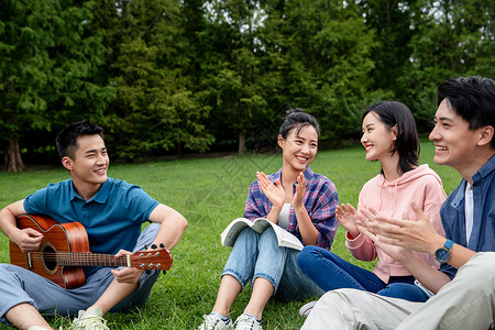 不看镜头愉悦满意快乐的大学生在草地上弹吉他唱歌图片