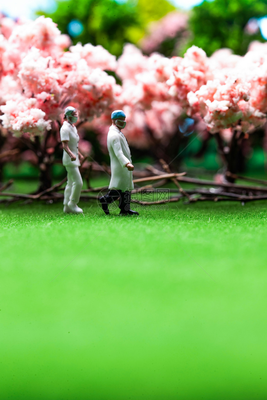 两个人人类形象守护樱花树旁草地上行走的医护人员图片