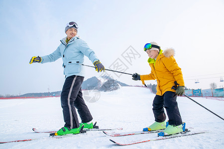 手套滑雪杖青年男人滑雪场上滑雪的快乐父子高清图片