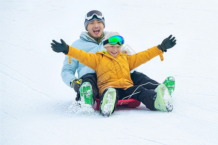 快乐父子坐着雪上滑板滑雪背景图片