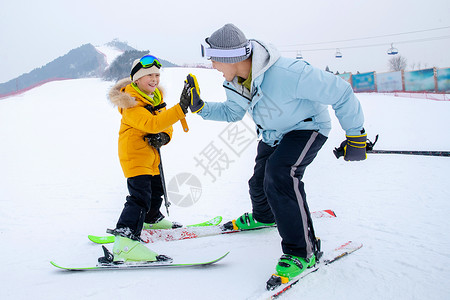 对视的爱滑雪场上击掌的快乐父子背景