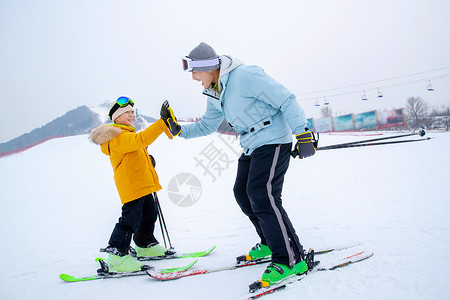 冬季滑雪男孩滑雪场上击掌的快乐父子背景