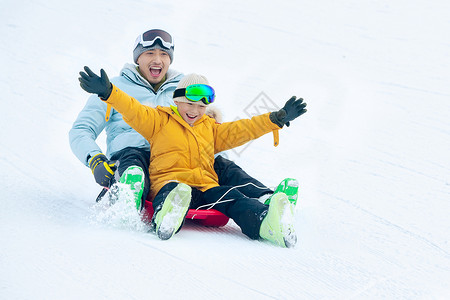 快乐父子坐着雪上滑板滑雪背景图片
