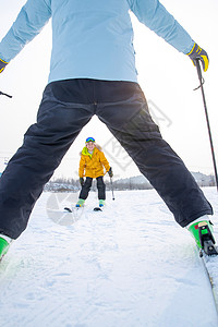 滑雪场上面对面滑雪的快乐父子图片