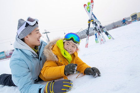 滑雪场内抱在一起打滚的快乐父子背景图片