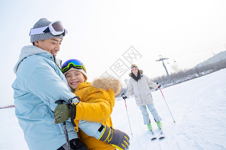 和母亲抱在一起滑雪场上抱在一起的父子和滑雪的母亲背景