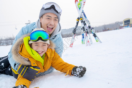 滑雪场内抱在一起打滚的快乐父子背景图片
