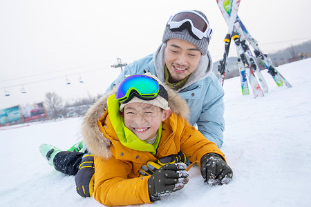 滑雪场内抱在一起打滚的快乐父子图片