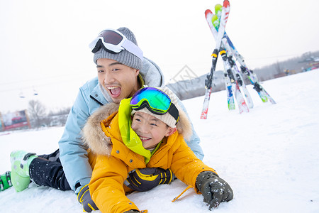 滑雪场内抱在一起打滚的快乐父子背景图片