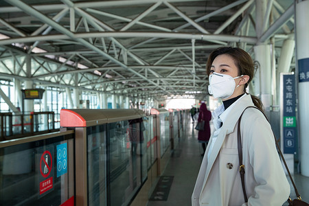 务戴口罩的年轻女人站在地铁站台上图片