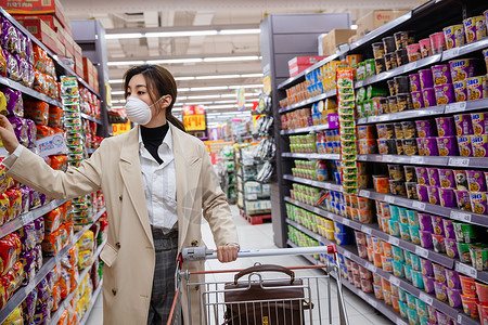 方便面货架戴口罩的青年女人在超市购物背景