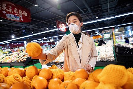 购物车货架戴口罩的青年女人在超市挑选水果图片