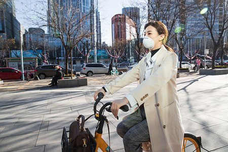 戴口罩骑车白领戴口罩的年轻女人骑共享单车背景