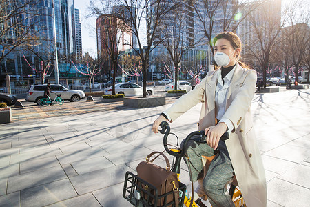 街道交通戴口罩的年轻女人骑共享单车图片