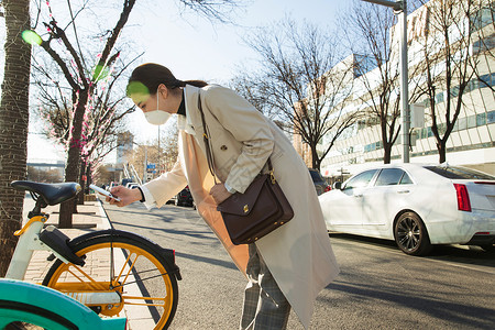 通勤戴口罩的年轻女人扫码骑共享单车图片