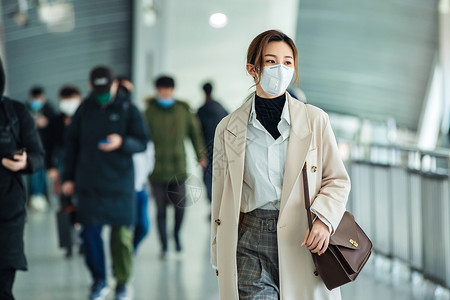 通勤者地铁月台戴口罩的年轻女人走在地铁站里背景图片