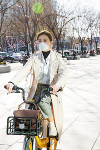 防流感口罩保护新型冠状戴口罩的年轻女人骑共享单车背景图片