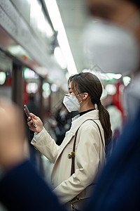交通安全设施戴口罩的年轻女人在地铁里看手机背景