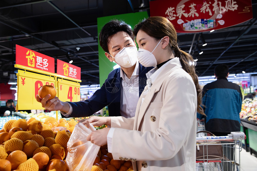 青年夫妇戴口罩在超市挑选水果图片