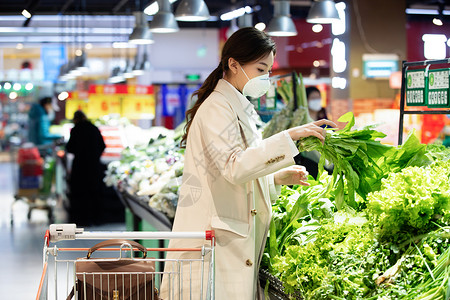 食品污染戴口罩的青年女人在超市购买青菜背景