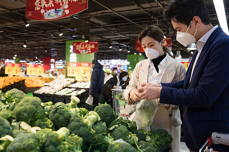 在超市购物的情侣青年夫妇戴口罩在超市购买青菜背景