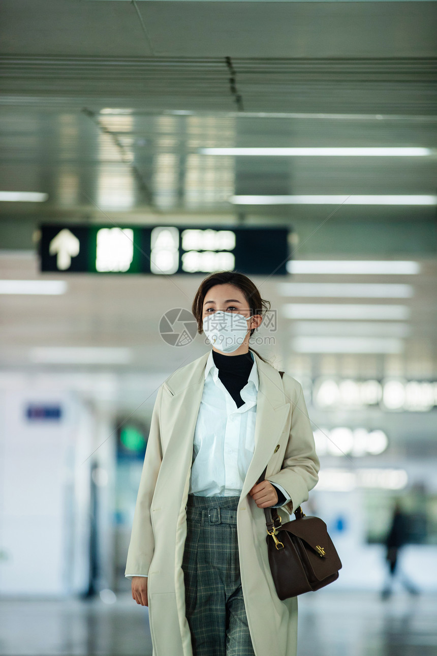 上班族戴口罩的年轻女人走在地铁站里图片