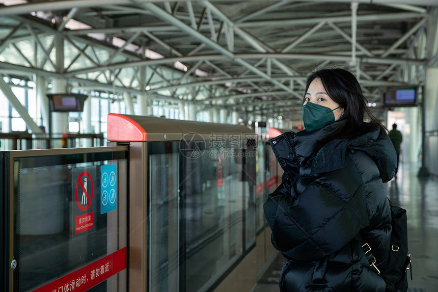戴口罩的年轻女人站在地铁站台上图片