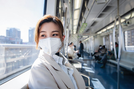 透过窗户往外看戴口罩的年轻女人乘坐地铁高清图片