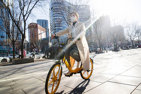 戴口罩骑车戴口罩的年轻女人骑共享单车背景
