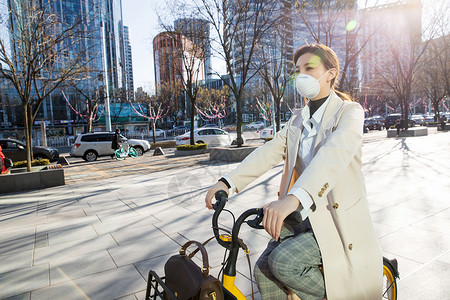 上班族戴口罩的年轻女人骑共享单车图片
