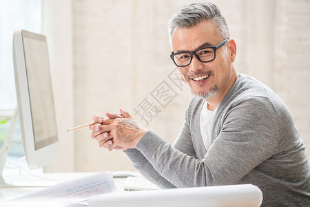 咧嘴笑的男士在室内研究图纸的中老年设计师男士背景