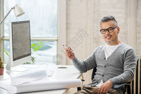 在室内研究图纸的中老年设计师男士高清图片