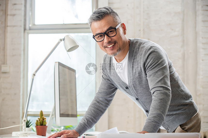 在室内研究图纸的中老年设计师男士图片