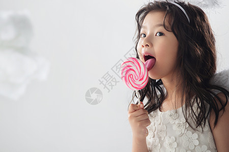 户内欢乐休闲装吃棒棒糖的可爱小女孩高清图片