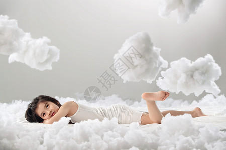 可爱软绵绵棉花云朵欢乐乐趣表现积极可爱的小女孩躺在云朵上背景