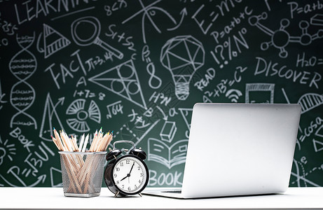 彩色英文标签黑板画前的桌子上笔记本电脑和文具背景