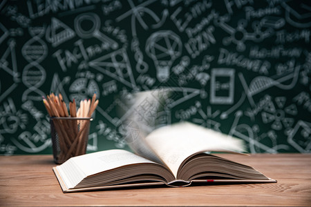 字母图形几何图形黑板画前的桌子上打开的书和笔筒背景