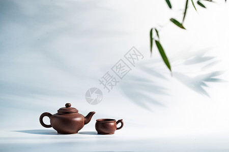绿叶装饰藤条竹叶下的茶壶和茶杯背景