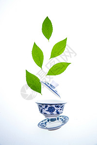 绿色的茶叶和瓷器茶杯图片