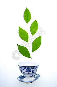新鲜叶脉茶叶和青花瓷茶杯图片