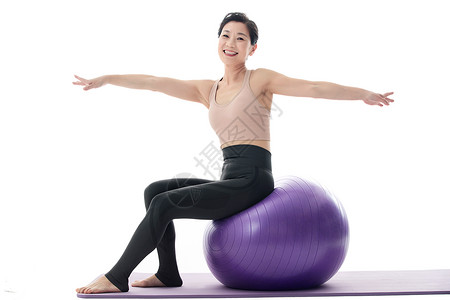中年女坐在瑜伽球上练习瑜伽高清图片