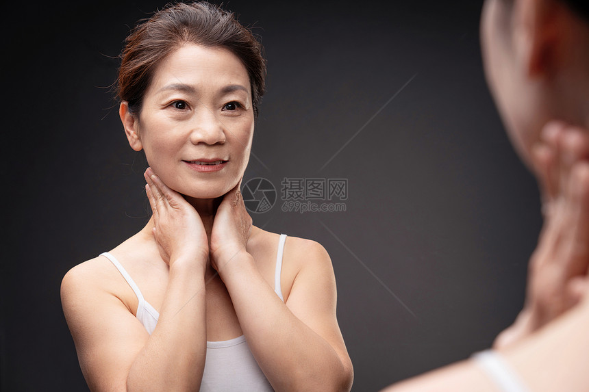 中年女人对着镜子做颈部护理图片