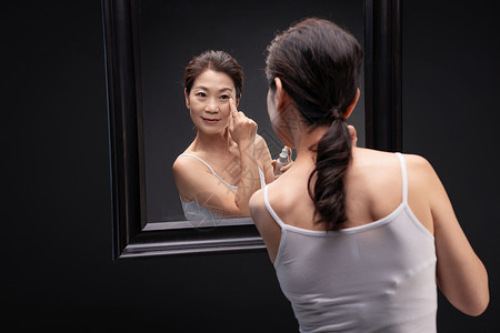 护肤品手指中年女人对着镜子涂抹爽肤水背景