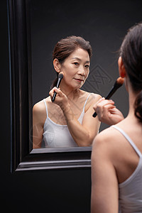 护肤美容对着镜子化妆的成熟女人图片