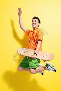 黑发男孩帅哥拿着滑板跳跃的青年男人背景
