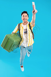 开心高举手臂人抱着行李箱去旅行的年轻男人图片