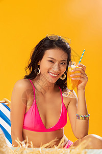 青年女人享乐沙滩坐在躺椅上喝饮料的比基尼美女图片